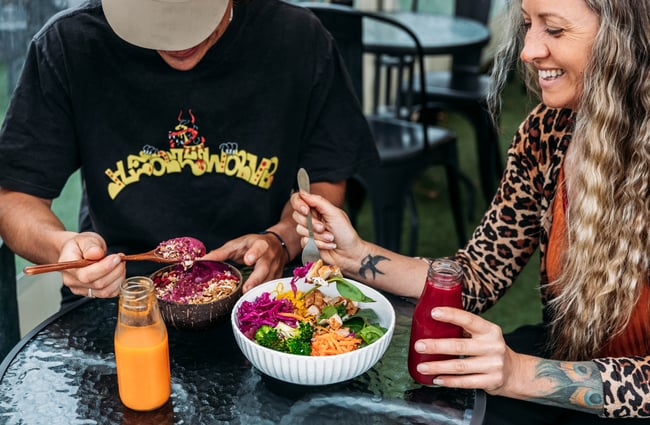 Two customers sit a table eating salad bowls with juices on the table at Dripping Bowl.