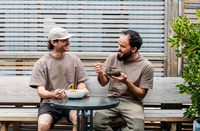 Two customers sitting at a table eating smoothie bowls at Dripping Bowl.