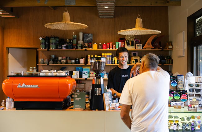 Barista talking to a customer by the coffee machine at Drop In Surf & Supply.