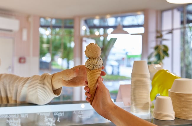 Customer reaching over the counter to take their ice cream cone at Duck Island.