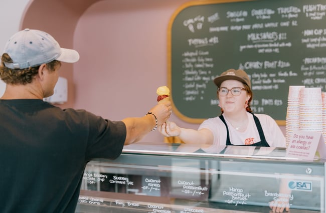 Customer reaching across for ice cream in a cone from server at Duck Island on High Street in Christchurch