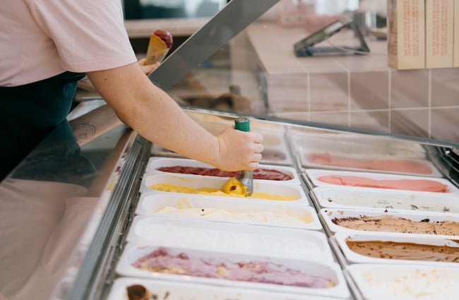 Close up of ice cream cabinet and staff scooping from the tub at Duck Island on High Street in Christchurch