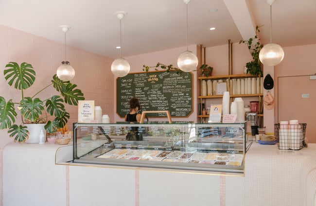 A staff member working behind a counter at a brightly decorated ice cream shop.