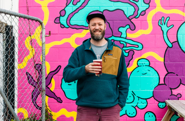 A man holding a beer smiling to camera.