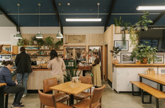 Customers waiting near the counter as a barista pours coffee at Dune Cafe.