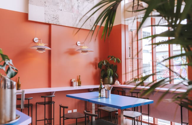 A blue high table with bench seats inside the restaurant.