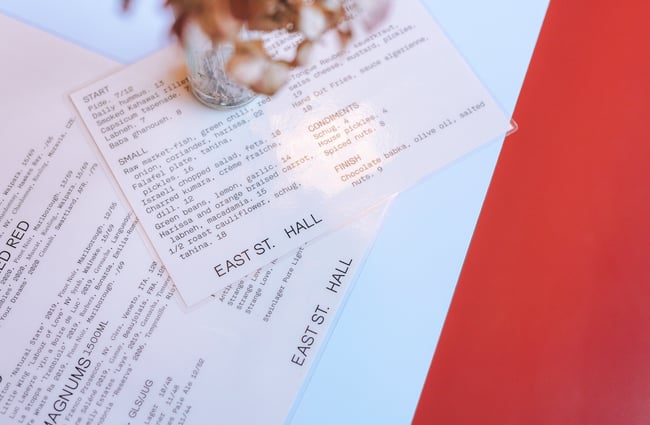 Close up of plastic covered white and black menus on a table.