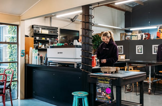 Barista standing behind coffee machine at Ebony Coffee Roasters.