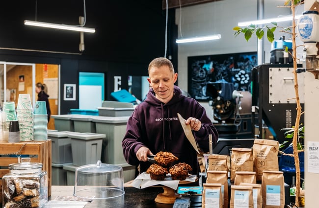 Barista selecting a muffin to serve at Ebony Coffee Roasters.