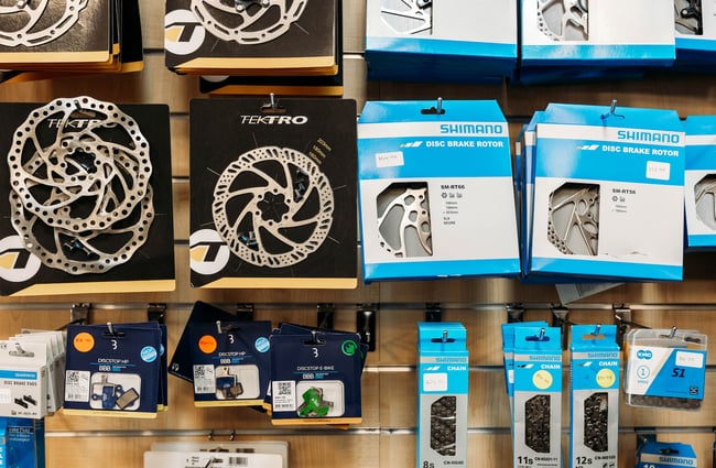 Close up of disc brakes, chains, and other bike components displayed for sale inside the store.