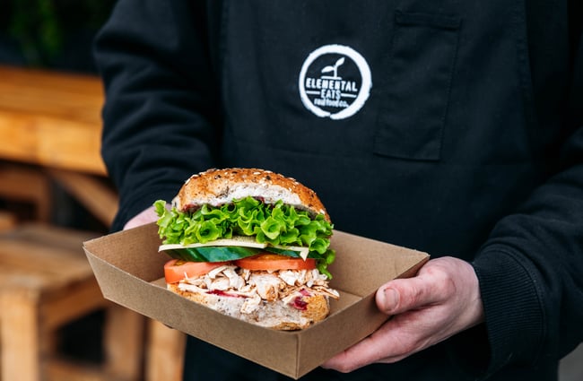 Person holding a burger at Elemental Eats.