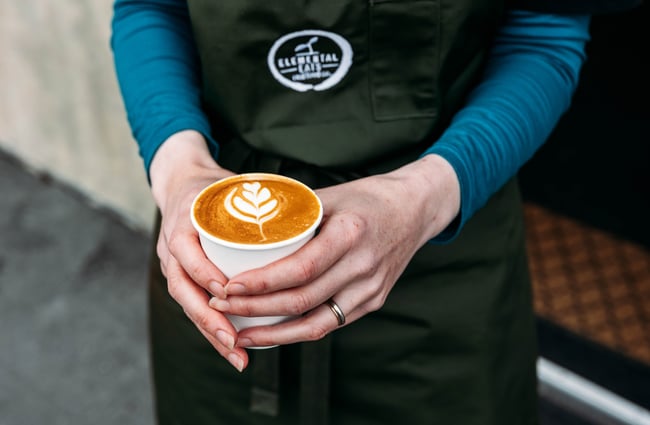 Person holding a coffee at Elemental Eats.