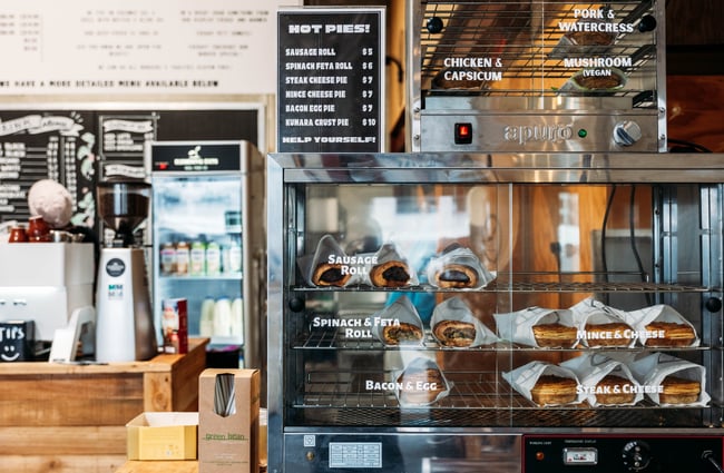 A pie warmer at the counter filled with sausage rolls at Elemental Eats.