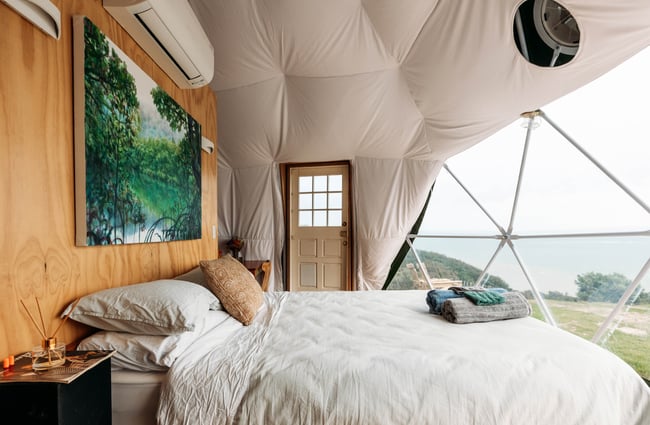 A well made bed inside a dome.