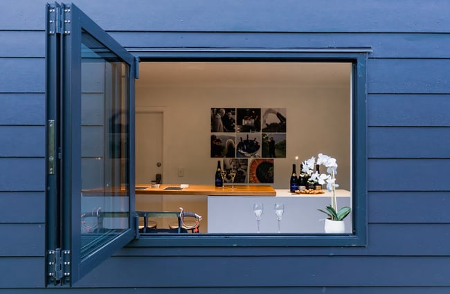 A blue exterior wall with an open window looking into a winery.