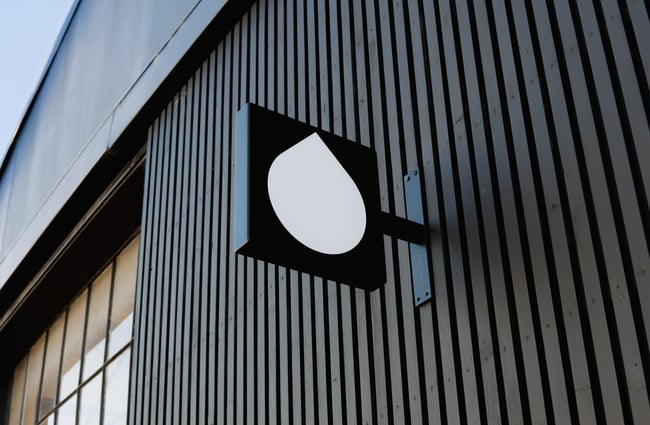A black and white sign on a black exterior wall.