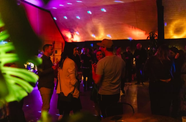 People chatting in the colourfully lit event space at an event at Evil Genius.