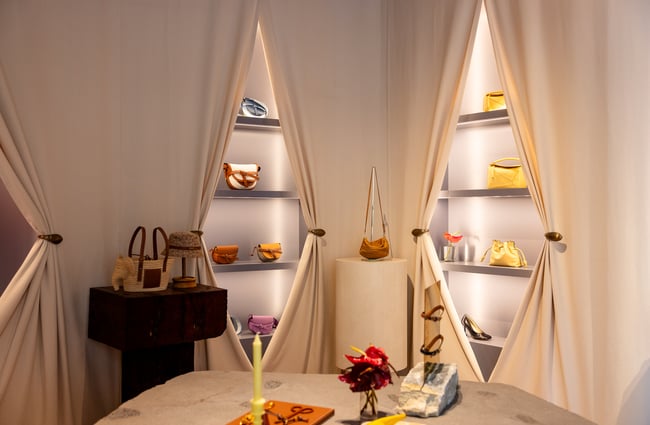 A selection luxury bags surrounded by cream curtains at retail shop