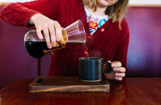 A woman drinking Chemex coffee.