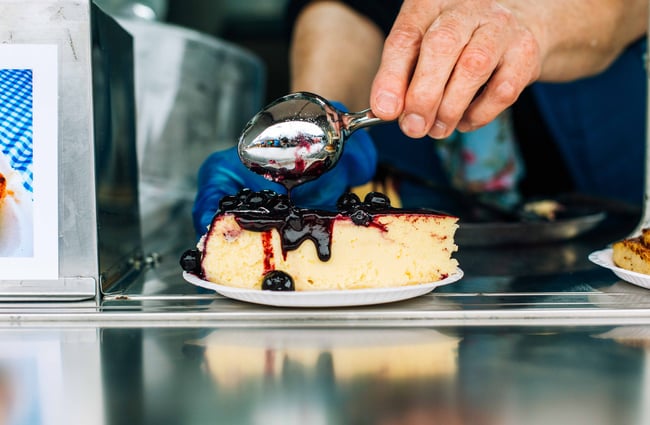 Blackcurrant sauce being poured onto cake.