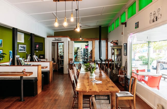 Rustic cafe dining area at Feliz & Sage in Kurow with a long wooden dining table and booths