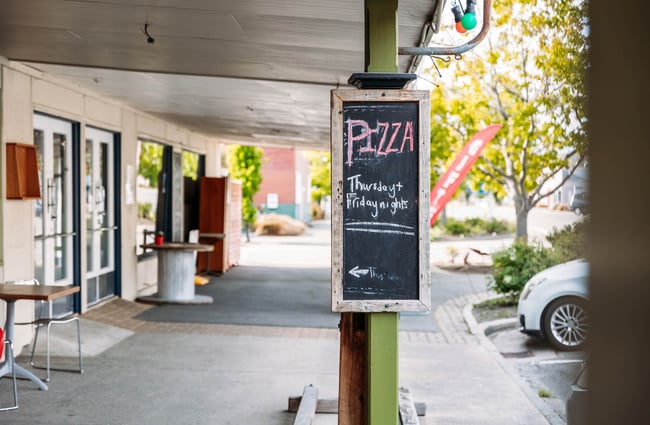 Blackboard sign outside cafe reading "Pizza Thursday & Friday Nights"