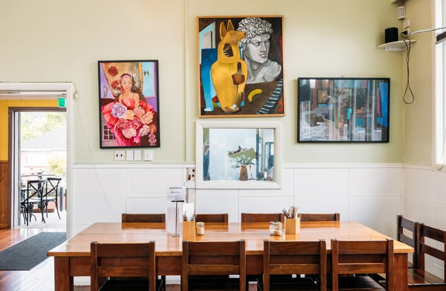 A large wooden table and chairs inside a brightly lit cafe.
