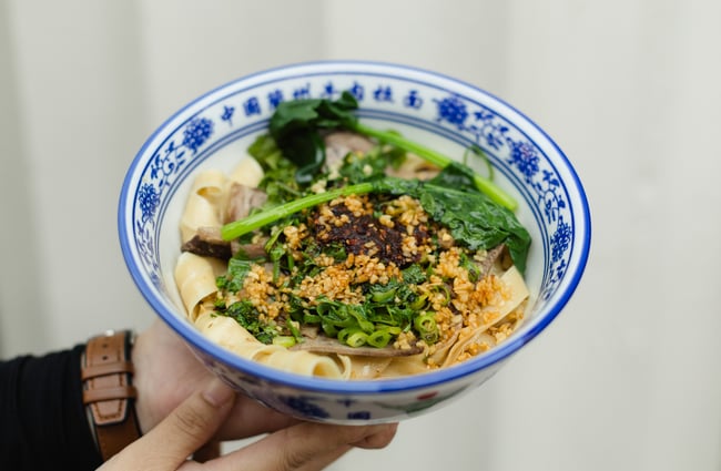 Bowl of noodles in a blue and white bowl at FJ Noodles & Dumplings.