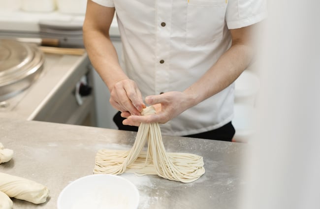 Chef making noodles in the kitchen at FJ Noodles & Dumplings.