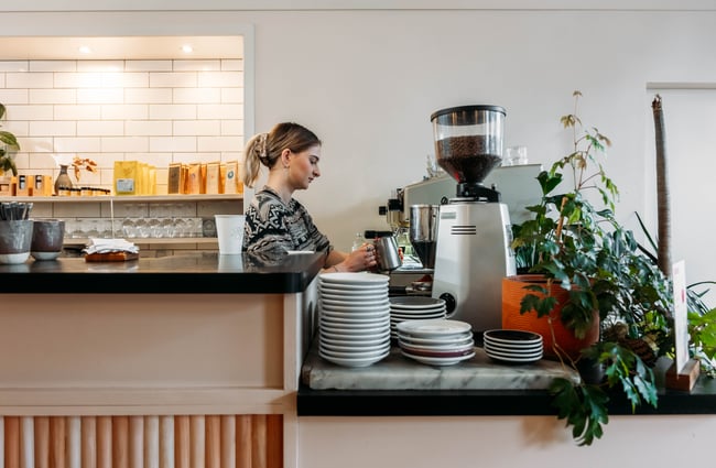 A woman making a coffee behind the counter at Flagship Eatery Gisborne.