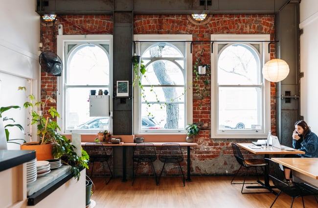 A cafe with a brick wall and large ceilings.