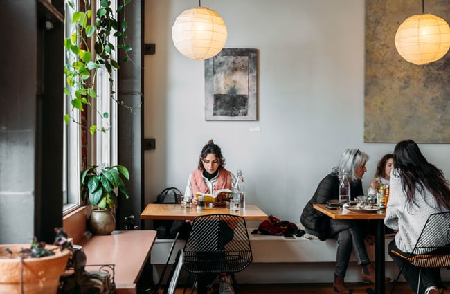 Customers sitting at tables inside a pretty cafe.