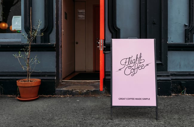 A pink 'Flight Coffee' pavement sign.