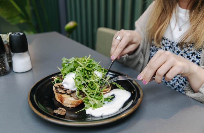 Woman about to eat poached eggs on toast.