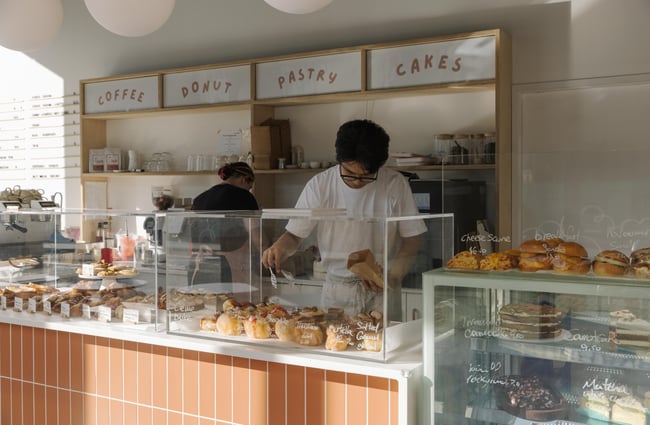 Team member selecting a pastry out of the cabinet at Fluffy Bake Shop.