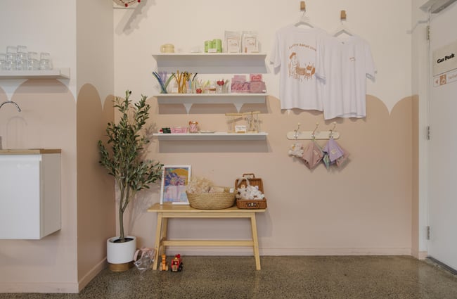 Merchandise corner with t-shirts and other items at Fluffy Bake Shop.