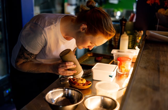 A close up of a chef making food in the kitchen at Forest.