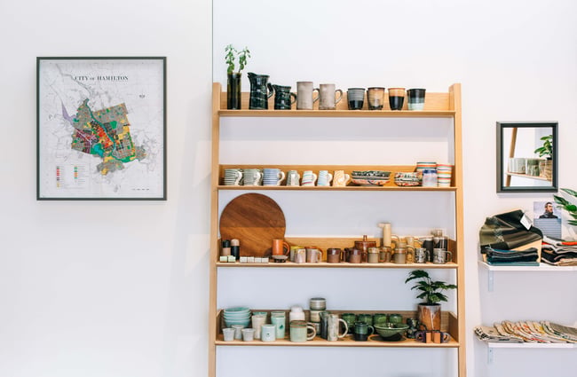 Ceramics on a wooden display against a white wall.