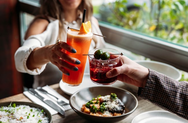 Two cocktails being held up by customers doing a cheers at Francesca.