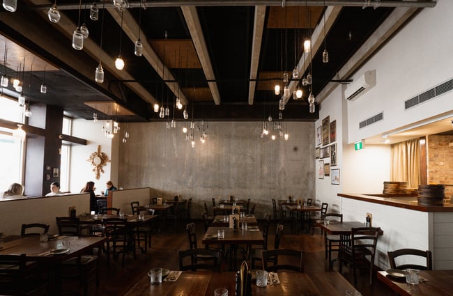 The large dining space inside a vast restaurant decorated in white and wood features.