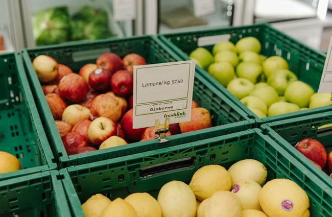 Green produce tubs filled with red and green apples and lemons.