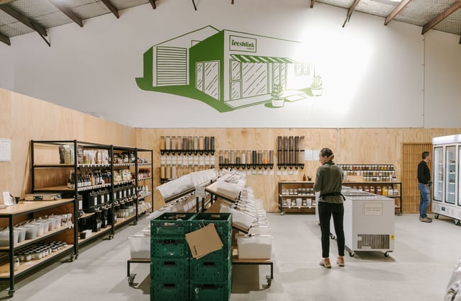 The interior of Freshlink Grocer where there is a costumer walking around shopping.