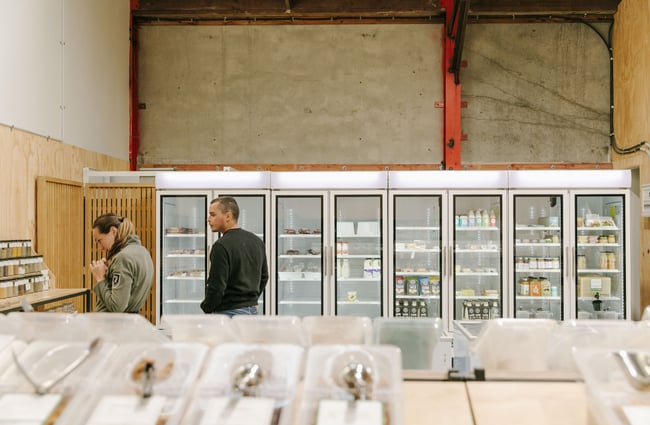 Two people looking in the produce refrigerators inside Freshlink Grocer.