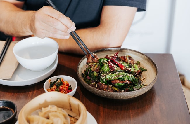 A hand reaching for a plate of food on a table.