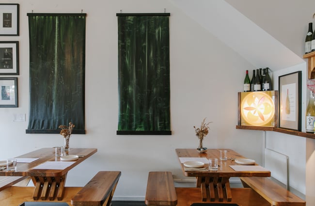 Tables and chairs sitting underneath green and black artwork.