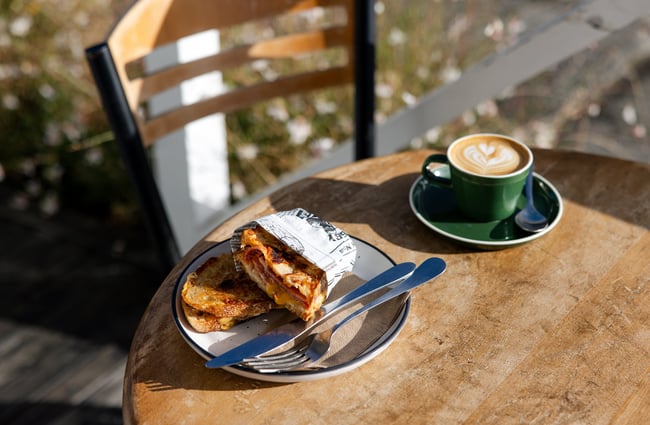 A cheese toastie and milky coffee on a table in the sun outside General Post.