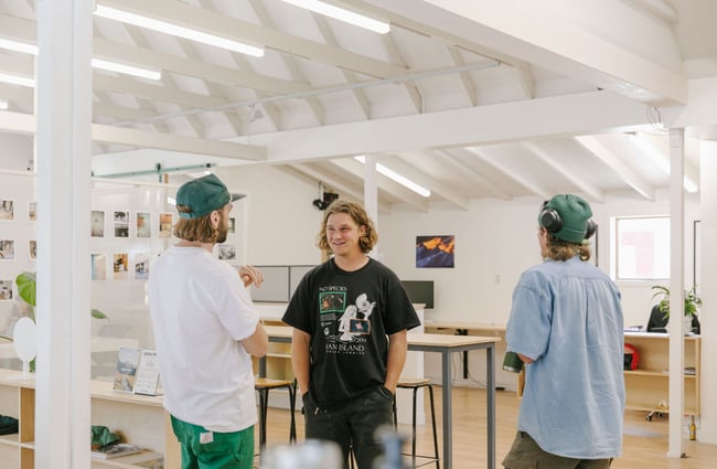 Three people standing around talking in the shared work space.