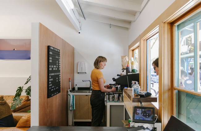 The little hole in the wall coffee shop with a lady ordering.