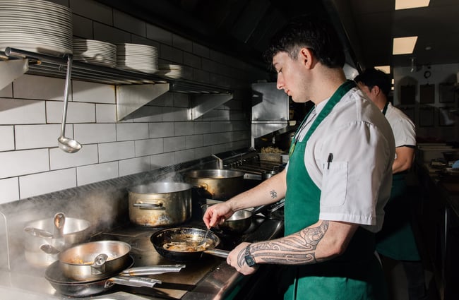 Chef cooking with pan at Gilt Brasserie in Auckland