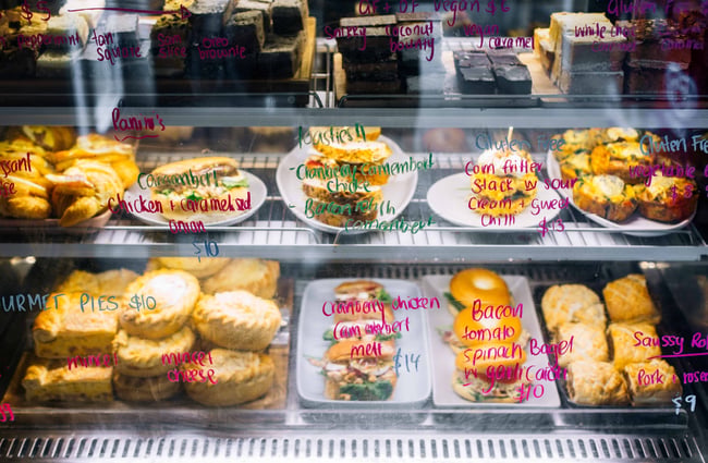 The glass food cabinet filled with lots of different colours of foods.